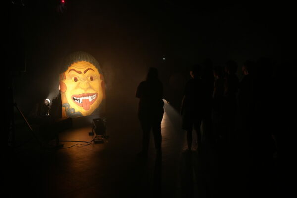 Personnes devant un visage peint sur une structure