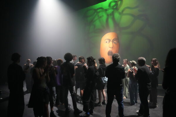 Foule sur scène devant un visage effaré, peint sur un support